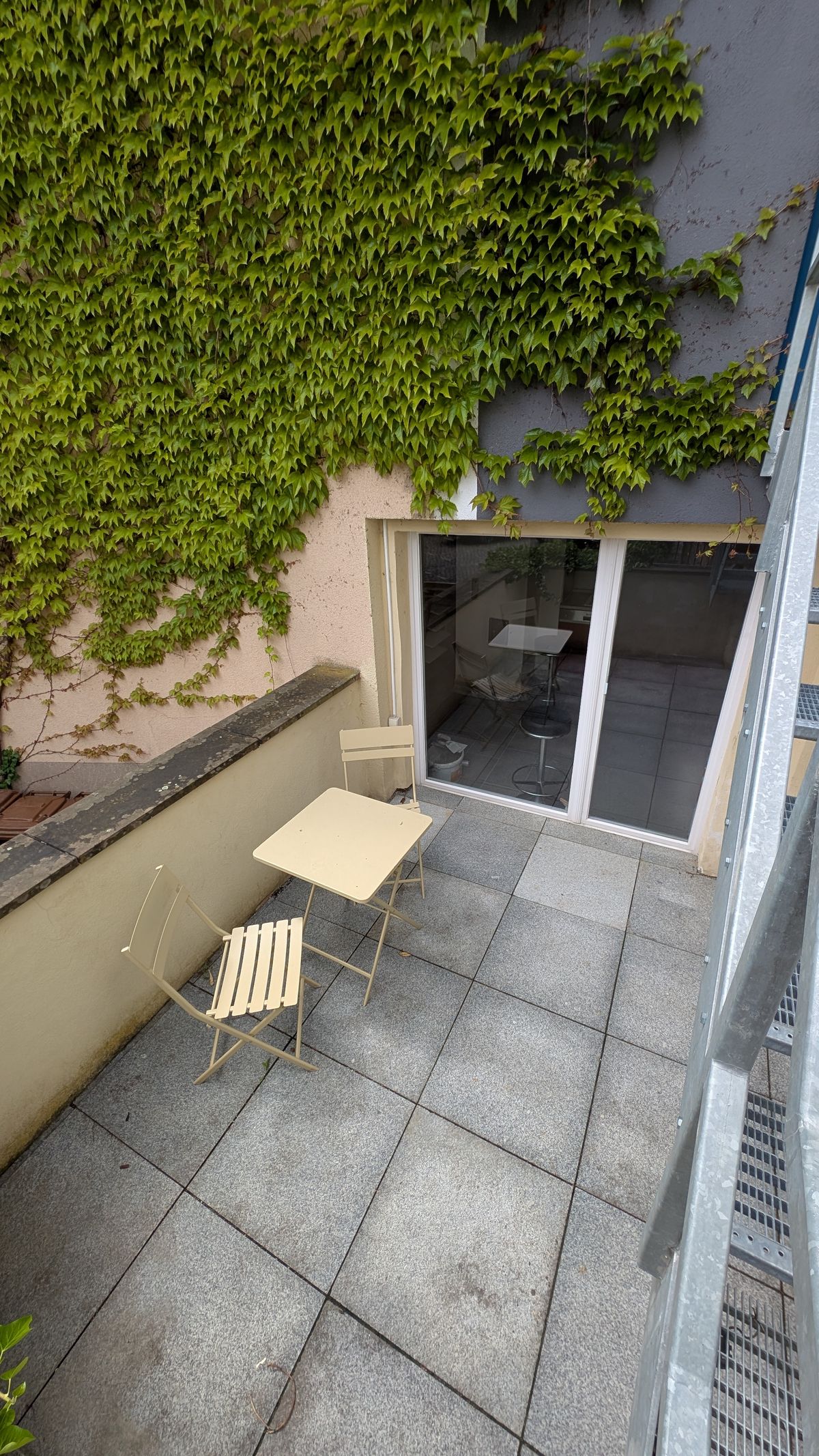 Kleine Terrasse mit Bistrotisch und Efeu-Wand